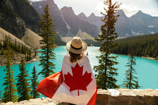 Lady wearing Canada's National Flag and in the background is a beautiful mountainous region